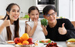 © atitaph - A happy Asian family spends lunch, vegetables, fruit, and dates at the table in their home. Cute little daughter having fun talking. Father, mother