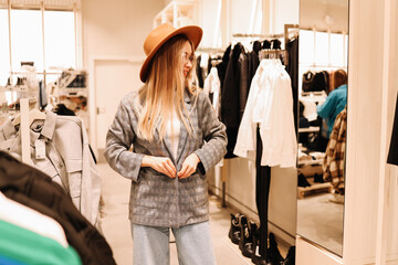 A smiling young shopaholic woman tries on clothes in a shopping mall store, walks through boutiques. Consumerism is a modern problem of society. Anti-environmental