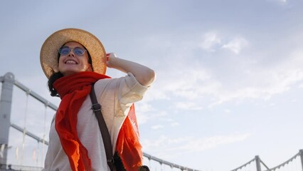 Wall Mural - Beautiful girl in a hat on the embankment near the bridge in summer