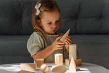 A Little Girl Plays And Learns Geometric Shapes On The Table. The Kid Builds A Tower From Wooden  Blocks. Learning Through Play. Developing Montessori Toddlers Activities.