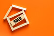 Real estate, Creative concept, House of wooden blocks with the inscription Sold, Beautiful orange background, Empty space