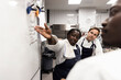 © Maskot - Female chef explaining colleagues over whiteboard in kitchen of restaurant
