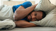 © Prostock-studio - African Guy Covering Ears With Pillow Having Insomnia In Bedroom
