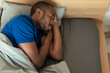 © Prostock-studio - High Angle Of Sleeping Black Guy Napping In Bed Indoors
