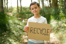 Child In The Forest Displays Sign With The Message "recycle"