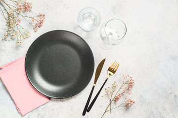 Sticker - Table setting with black plate, flowers and cutlery at white kitchen table. Top view with space for design.