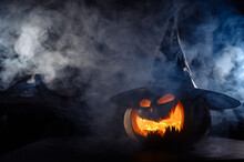 A Creepy Pumpkin With A Carved Grimace In The Smoke. Jack O Lantern In The Dark.