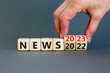 © Dzmitry - 2023 News new year symbol. Businessman turns a wooden cube and changes words News 2022 to News 2023. Beautiful grey table grey background, copy space. Business 2022 news new year concept.