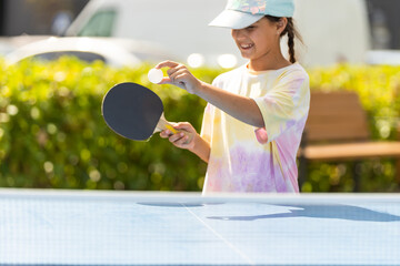 Little girl playing ping pong in park.