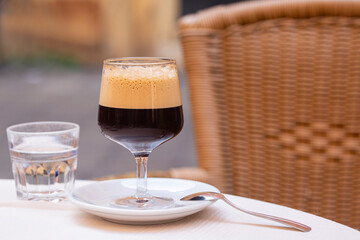 Sticker - Caffè shakerato in a tall glass, in an outdoor italian cafe. Cold shaked coffee with a foam made in a shaker with ice.