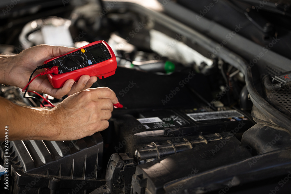 Foto Mechanic doing car inspection, he is testing car battery with ...