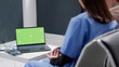 © DC Studio - Modern laptop with greenscreen display on table in reception lobby, people chatting about healthcare. Blank copyspace with isolated mockup template and chroma key background in waiting room.
