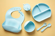 Food grade silicone baby self feeding utensils set on color background. Flat lay, top view.