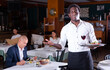 © JackF - Hospitable smiling african american waiter standing with serving tray in cozy restaurant, greeting guests