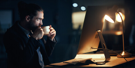 Coffee, night and commitment with a business man working late in a dark office on a deadline. Male corporate professional at work on a computer at his desk for a global or international project