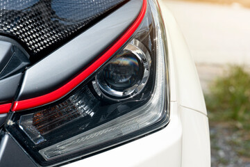 Wall Mural - Abstract of luxury or used of headlights of car. Car in the parking lot with blurred of green grass outside at day.