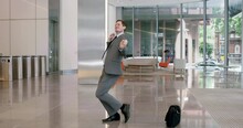 Happy Businessman Winner Dancing After Success And Victory In The Office Lobby In Suit And Tie In Celebration. Corporate, Celebrate And Funny Guy With Energy, Dance And Excited About A Job Promotion