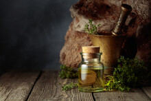 Bottle Of Thyme Essential Oil With Fresh Thyme Twigs.