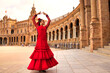 Leinwanddruck Bild - Beautiful teenage woman dancing flamenco in a square in Seville, Spain. She wears a red dress with ruffles and dances flamenco with a lot of art. Flamenco cultural heritage of humanity.