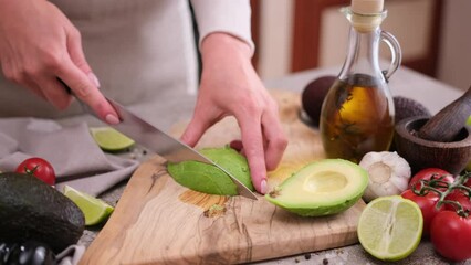 Wall Mural - Healthy food nutrition cuisine recipes - Cutting slicing fresh avocado fruit with knife on a wooden board in a kitchen