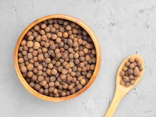 Wall Mural - Spice Allspice (Jamaica pepper, Pimento) in wooden bowl and spoon on gray concrete background. Top view. Healthy eating concept