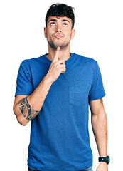 Poster - Young hispanic man wearing casual t shirt thinking concentrated about doubt with finger on chin and looking up wondering