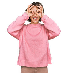 Canvas Print - Young hispanic woman wearing casual clothes doing ok gesture like binoculars sticking tongue out, eyes looking through fingers. crazy expression.