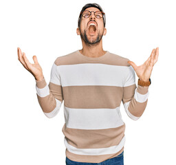 Wall Mural - Handsome man with beard wearing casual clothes and glasses crazy and mad shouting and yelling with aggressive expression and arms raised. frustration concept.