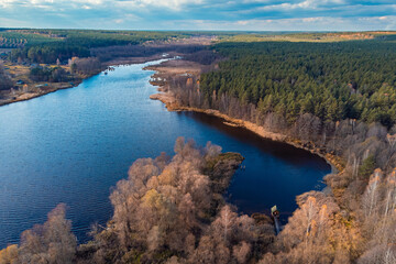 Canvas Print - Aerial view of lake near small village and pine forest. Autumn nature, drone point of view