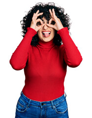 Sticker - Young middle east girl wearing casual clothes and glasses doing ok gesture like binoculars sticking tongue out, eyes looking through fingers. crazy expression.