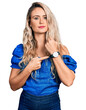 © Krakenimages.com - Young blonde woman wearing casual clothes in hurry pointing to watch time, impatience, looking at the camera with relaxed expression