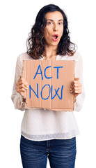 Wall Mural - Young beautiful hispanic woman holding act now banner scared and amazed with open mouth for surprise, disbelief face