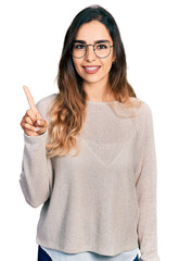 Wall Mural - Beautiful hispanic woman wearing casual sweater and glasses pointing finger up with successful idea. exited and happy. number one.