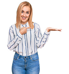 Wall Mural - Beautiful caucasian woman wearing casual clothes amazed and smiling to the camera while presenting with hand and pointing with finger.