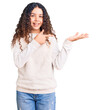 © Krakenimages.com - Beautiful kid girl with curly hair wearing casual clothes amazed and smiling to the camera while presenting with hand and pointing with finger.
