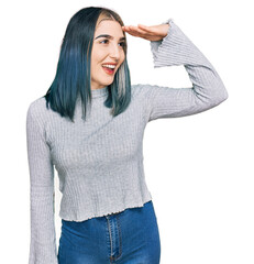 Wall Mural - Young modern girl wearing casual sweater very happy and smiling looking far away with hand over head. searching concept.