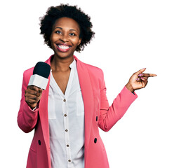 Wall Mural - African american woman with afro hair holding reporter microphone smiling happy pointing with hand and finger to the side