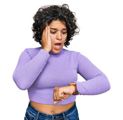 Canvas Print - Young hispanic woman with curly hair wearing casual clothes looking at the watch time worried, afraid of getting late