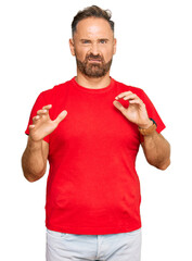 Sticker - Handsome middle age man wearing casual red tshirt disgusted expression, displeased and fearful doing disgust face because aversion reaction. with hands raised