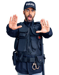 Sticker - Young hispanic man wearing police uniform doing stop gesture with hands palms, angry and frustration expression