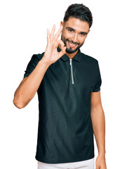 Canvas Print - Young man with beard wearing sportswear smiling positive doing ok sign with hand and fingers. successful expression.