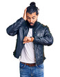 Young arab man wearing casual leather jacket looking at the watch time worried, afraid of getting late