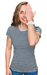 Canvas Print - Young blonde woman wearing casual clothes covering one eye with hand, confident smile on face and surprise emotion.