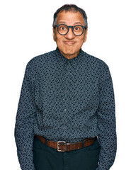 Canvas Print - Middle age indian man wearing casual clothes and glasses puffing cheeks with funny face. mouth inflated with air, crazy expression.