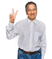 Poster - Middle age indian man wearing casual white shirt smiling with happy face winking at the camera doing victory sign. number two.