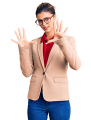 Poster - Young beautiful woman wearing business shirt and glasses afraid and terrified with fear expression stop gesture with hands, shouting in shock. panic concept.