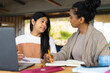 © Wavebreak Media - Biracial mother writing in book while teaching teenager daughter on table at home
