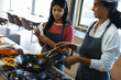© Wavebreak Media - Biracial teenage girl looking at mother cooking food on stove in kitchen, copy space