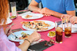 © Ladanifer - Unrecognizable mature adults eating pizza at a restaurant. Anonymous group of people at a bar.