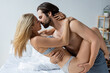 © LIGHTFIELD STUDIOS - side view of shirtless man holding and kissing sexy blonde woman in bedroom.